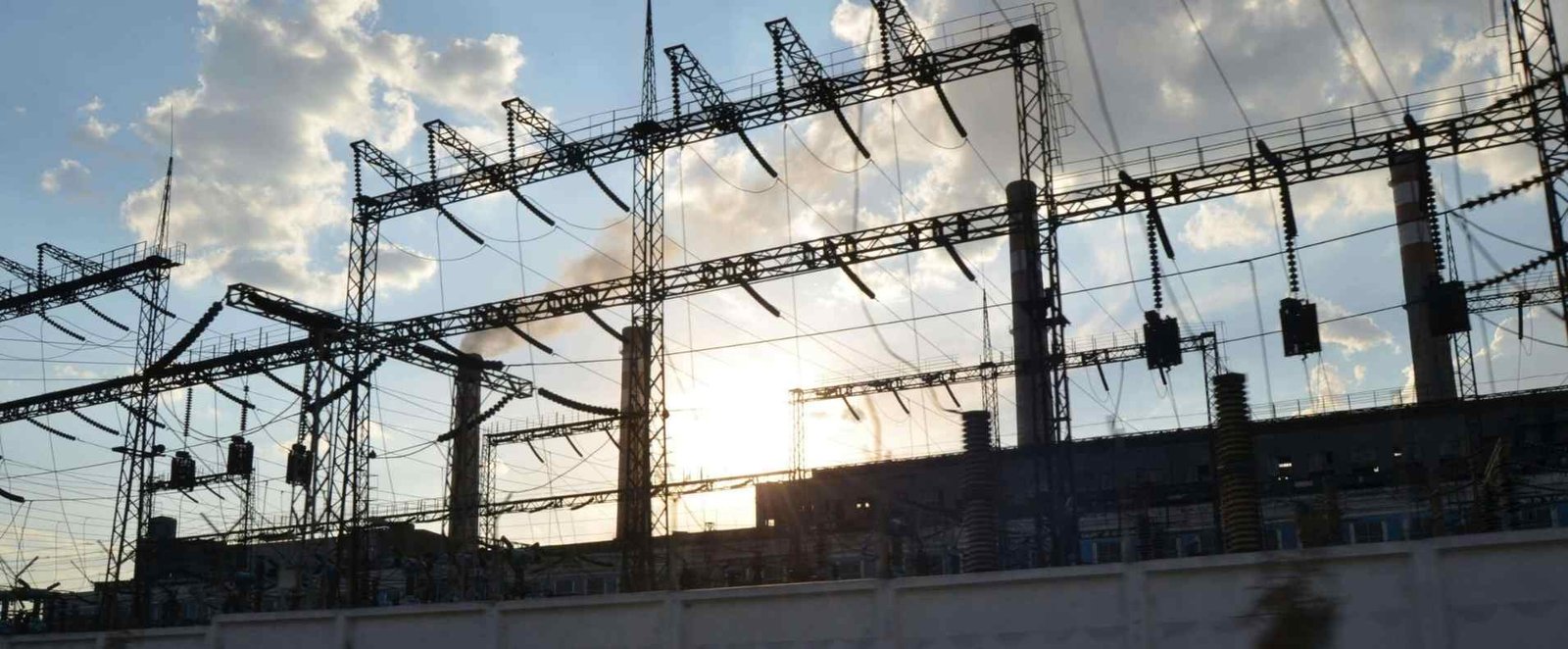 Imagen de una central electrica y de fondo se ve el cielo celeste con nubes